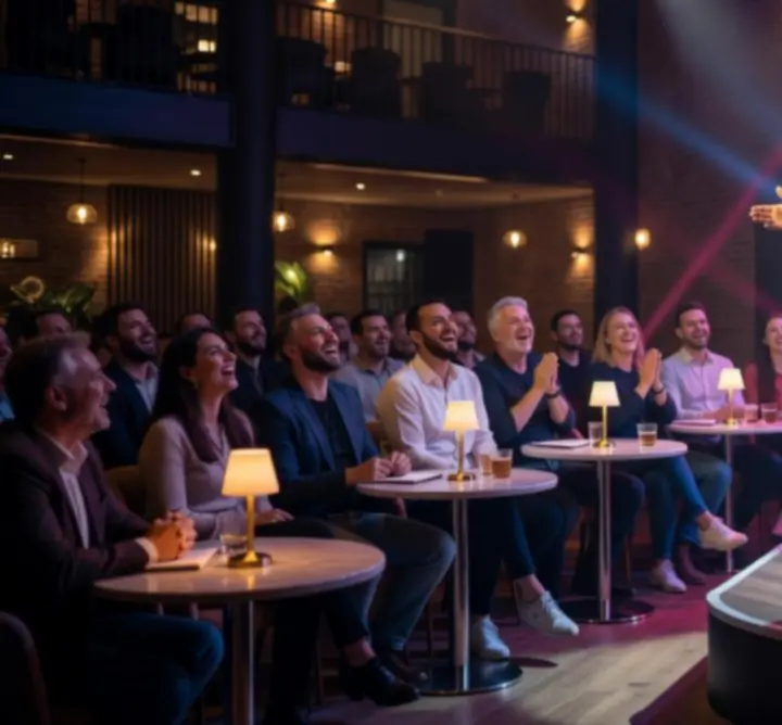 Stand-up humorista színpadon, nevető közönséggel egy modern rendezvényhelyszínen